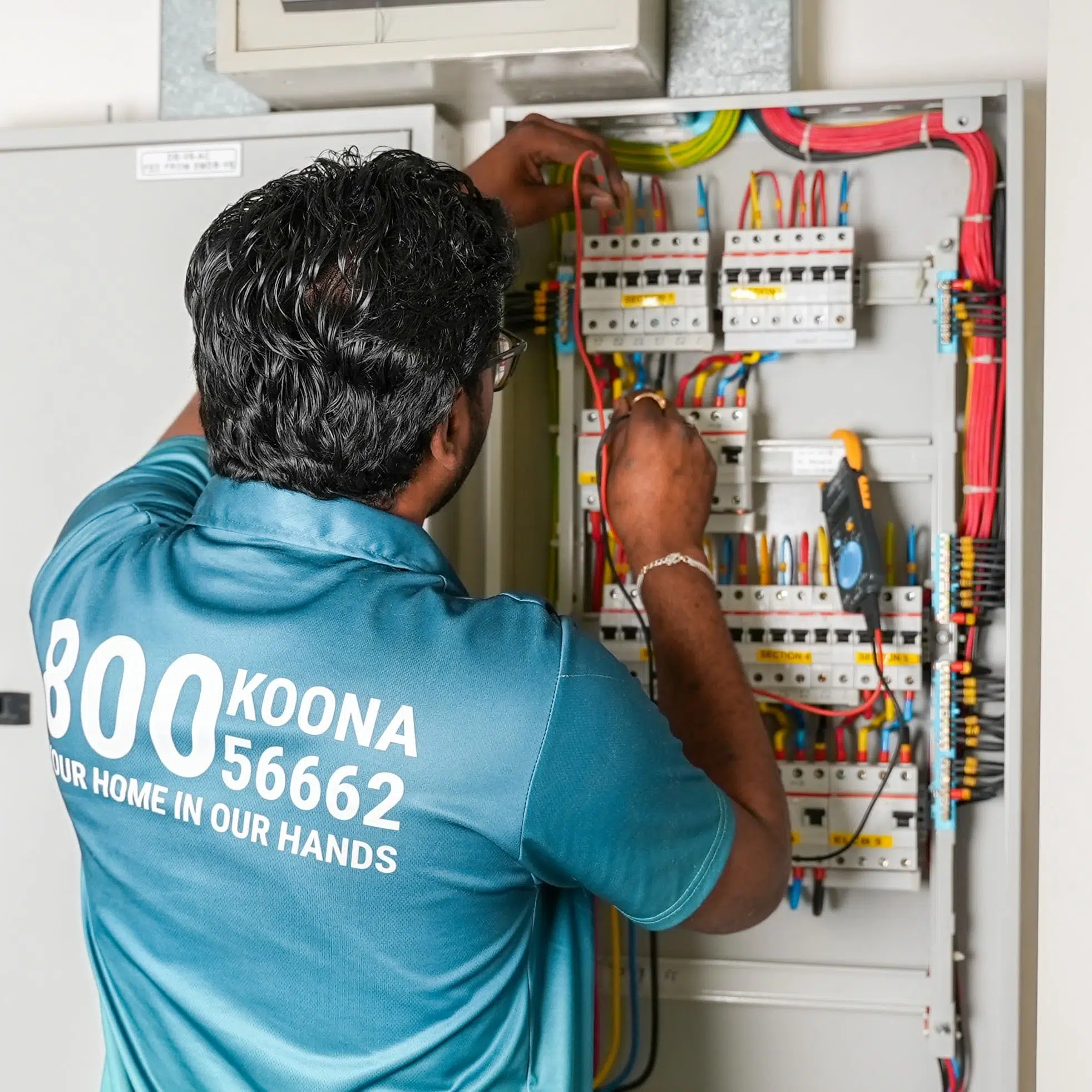 Electrical service in Dubai technician repairing a residential circuit breaker panel, inspecting wiring and connections inside an open electrical distribution board.