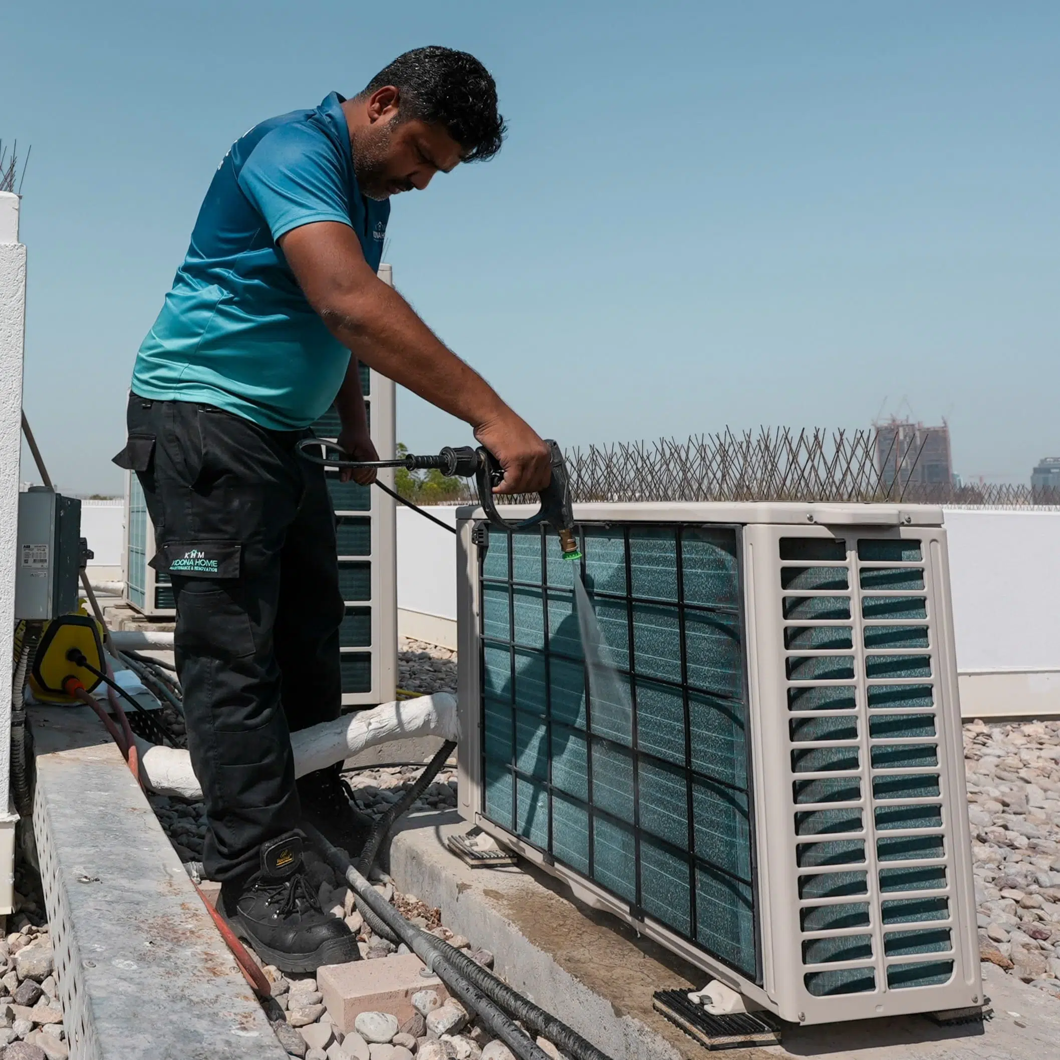 Technician performing air conditioner cleaning on rooftop unit as part of Annual Maintenance Contract (AMC) service
